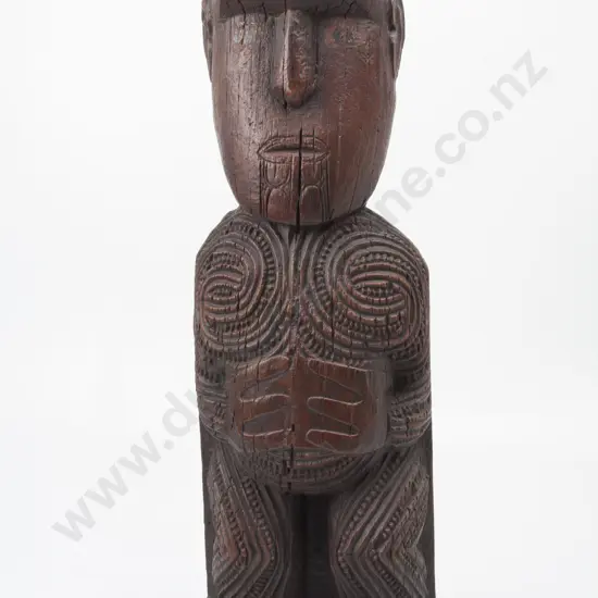 C19th or late C18th Maori carved figure (possibly a tekoteko). Red stained with faint traces of paint to eyes. Carved female moku to chin with both hands to stomach. Geometric spiral and notch carving to body. H. 61cm