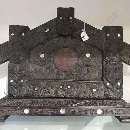 A Ngati Tarawhai photo frame. Carved in the form of a wharenui entrance. The amo with ancestral figures with inset paua shell eyes