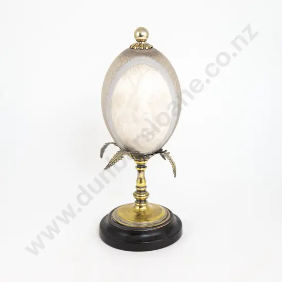 An Australian Carved Emu Egg On A Brass Turned Stand With Black Ebonised Base